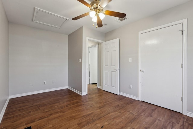 unfurnished bedroom featuring visible vents, baseboards, attic access, wood finished floors, and a ceiling fan