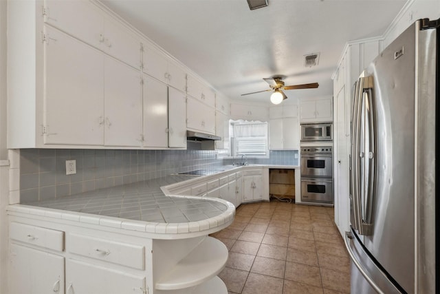 kitchen featuring visible vents, decorative backsplash, white cabinets, under cabinet range hood, and appliances with stainless steel finishes