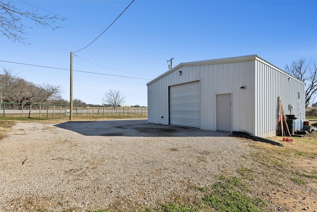 detached garage featuring driveway and fence