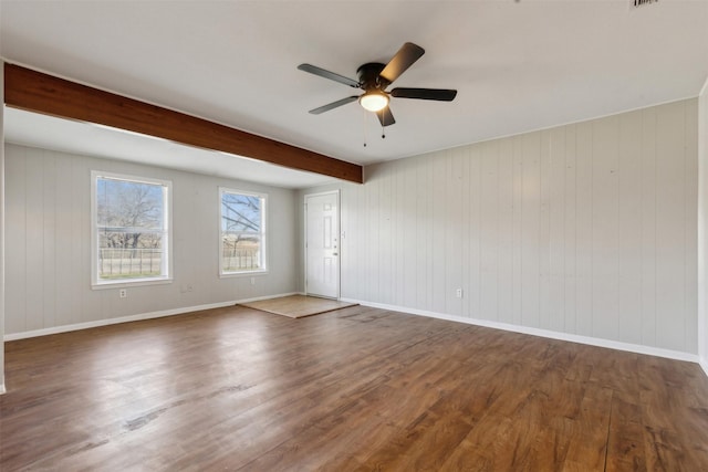 spare room featuring baseboards, beam ceiling, a ceiling fan, and dark wood-style flooring