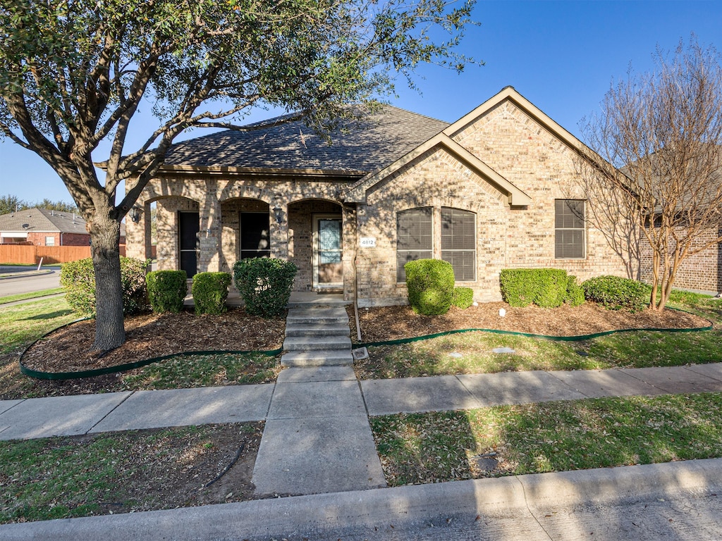 french country style house with a porch and brick siding