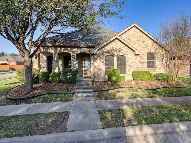 french country style house with a porch and brick siding