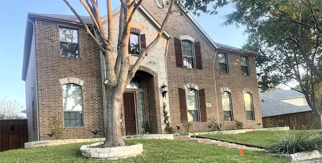 view of front of house featuring stone siding, brick siding, and a front lawn