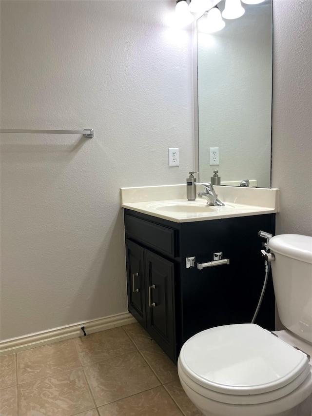 half bath featuring tile patterned flooring, toilet, vanity, and baseboards