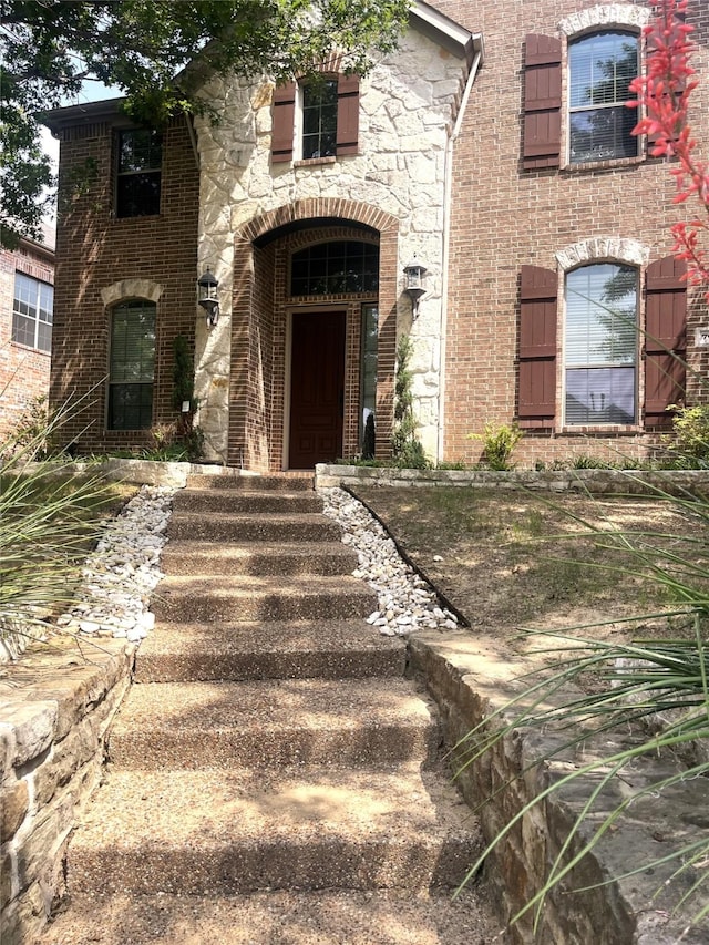 property entrance with stone siding and brick siding