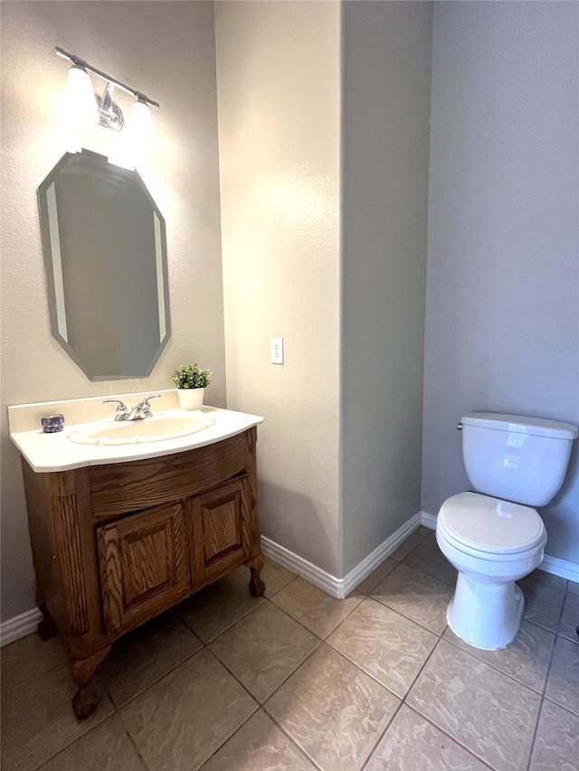 bathroom featuring baseboards, toilet, vanity, and tile patterned flooring