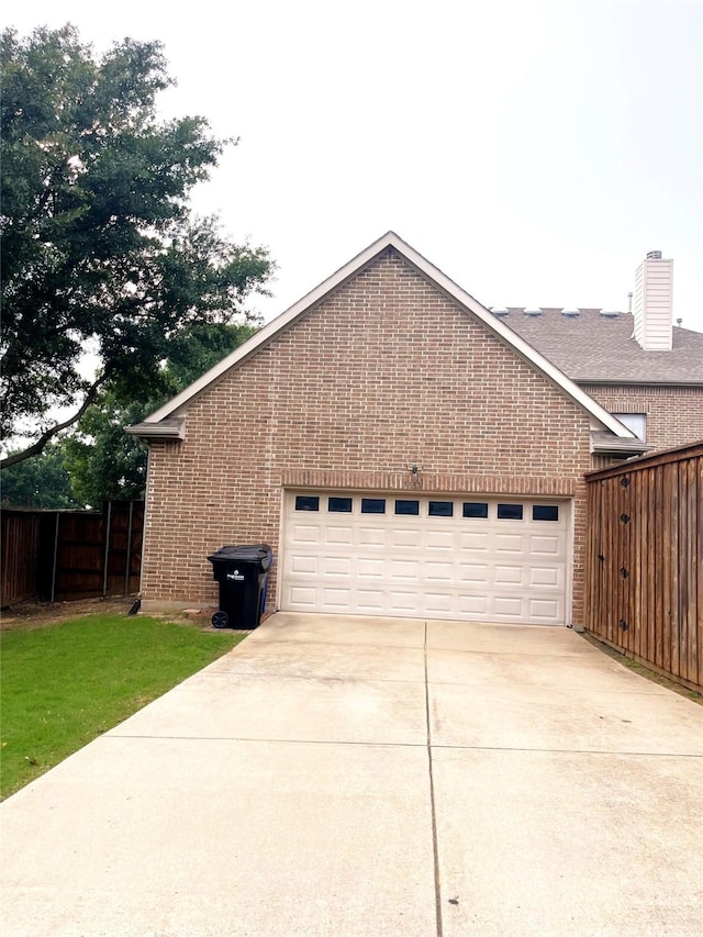 view of side of home featuring concrete driveway, a garage, fence, and brick siding