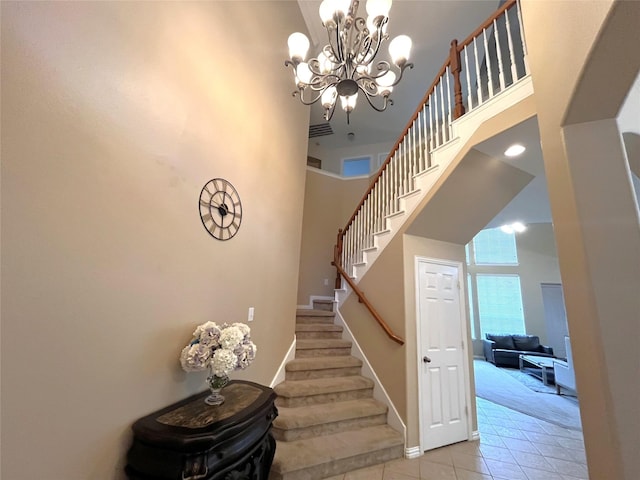 stairs featuring tile patterned floors, baseboards, a notable chandelier, and a towering ceiling