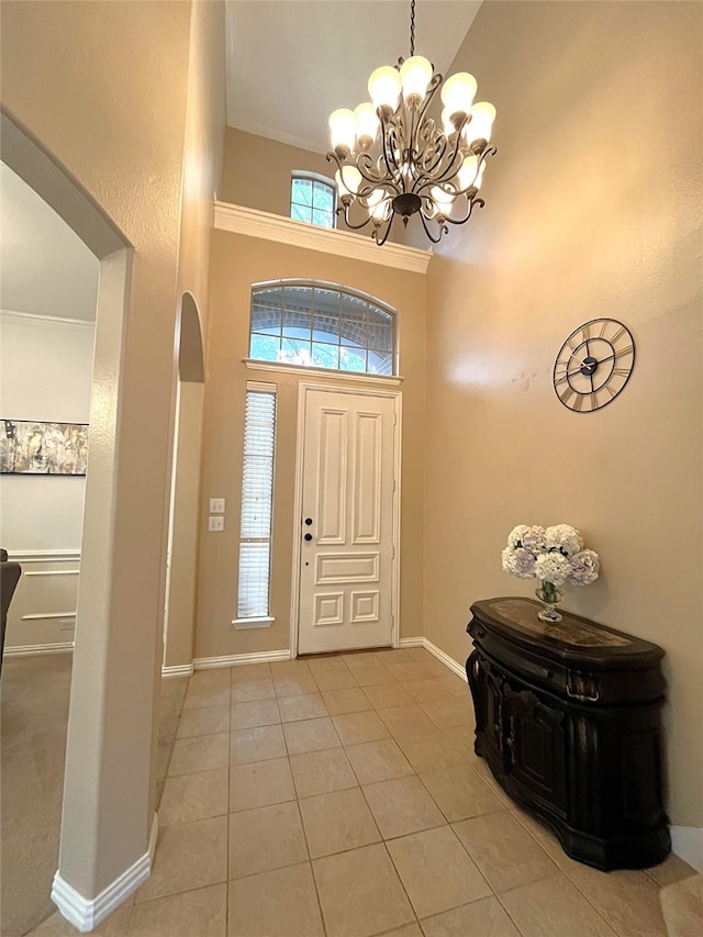 entryway with light tile patterned floors, baseboards, high vaulted ceiling, an inviting chandelier, and arched walkways