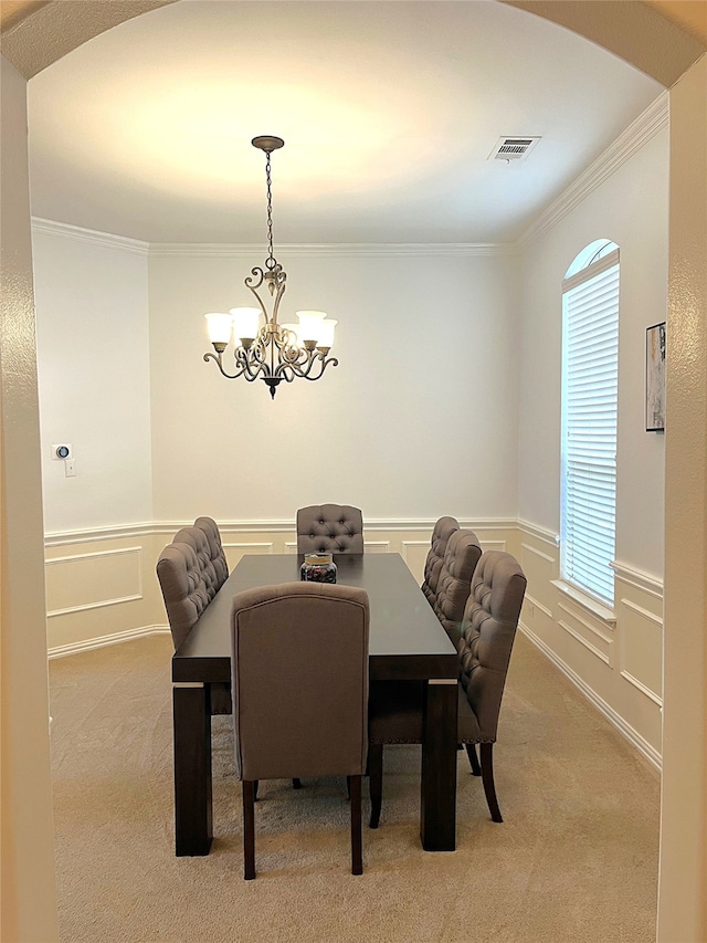 dining room with ornamental molding, light colored carpet, a wainscoted wall, and a chandelier