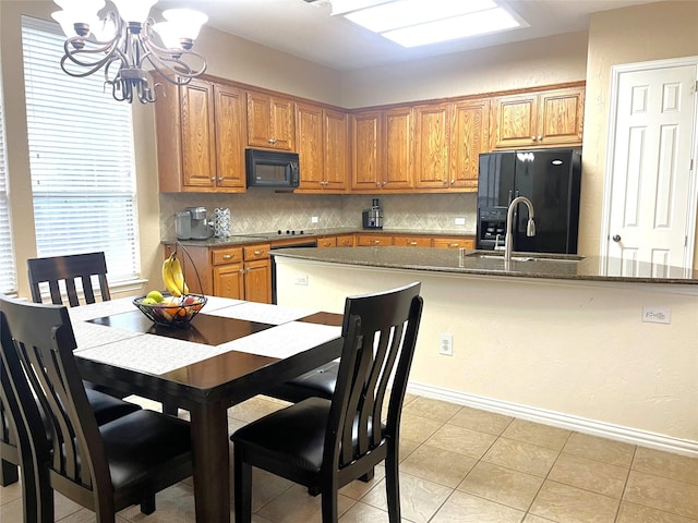 kitchen with backsplash, dark stone countertops, brown cabinetry, black appliances, and a sink