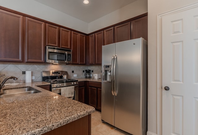 kitchen with light stone counters, backsplash, appliances with stainless steel finishes, and a sink