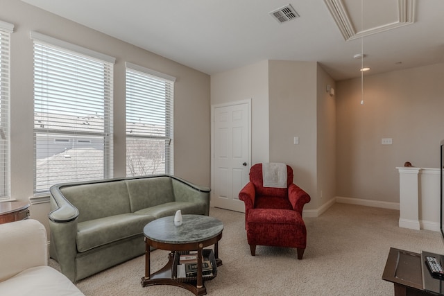 living area with visible vents, light colored carpet, attic access, and baseboards