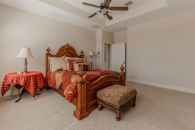 bedroom featuring a tray ceiling, visible vents, baseboards, and light carpet