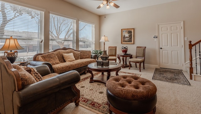 living area with stairs, baseboards, carpet floors, and a ceiling fan