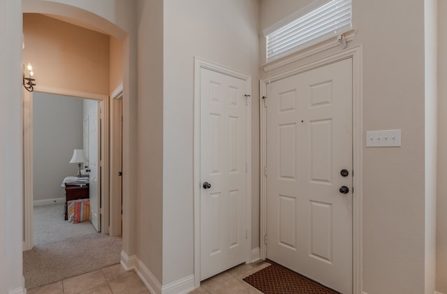 foyer with light tile patterned flooring, light colored carpet, and baseboards