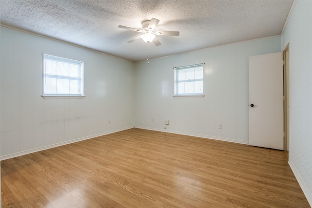 spare room with a textured ceiling, light wood finished floors, a ceiling fan, and baseboards