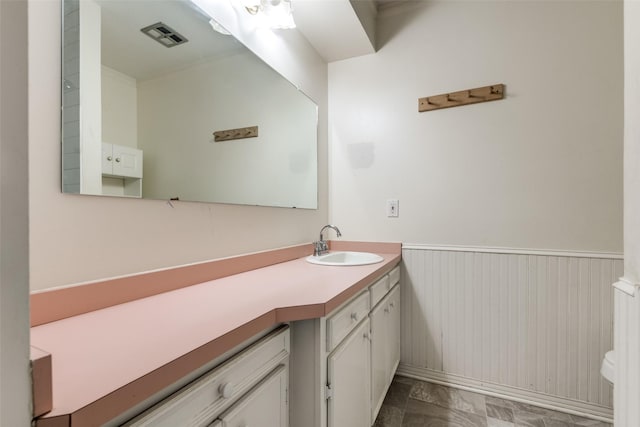 bathroom with toilet, visible vents, wainscoting, and vanity