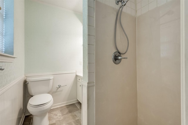 full bath featuring a wainscoted wall, vanity, a tile shower, and toilet