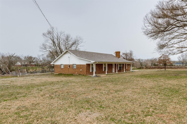 exterior space with a front yard, a chimney, a porch, and brick siding