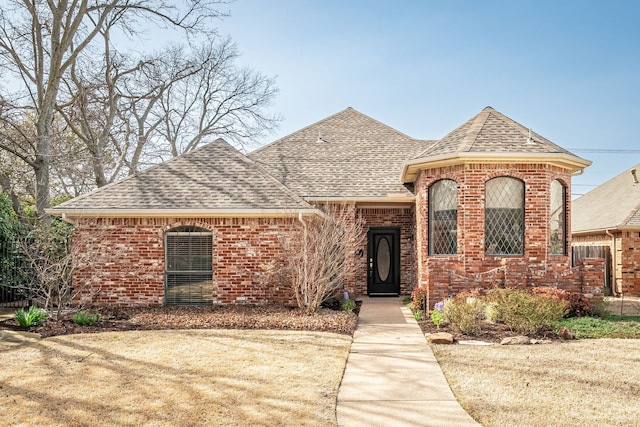 french country inspired facade featuring brick siding and roof with shingles