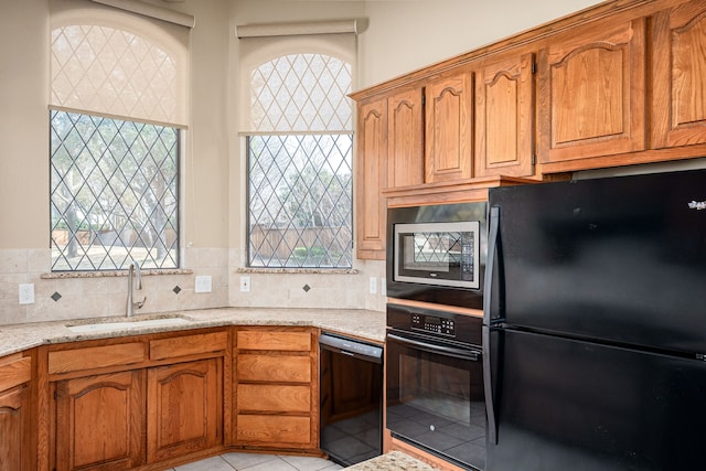 kitchen with black appliances, tasteful backsplash, brown cabinets, and a sink