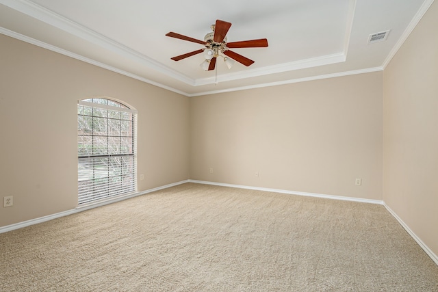 carpeted spare room featuring crown molding, a raised ceiling, visible vents, a ceiling fan, and baseboards