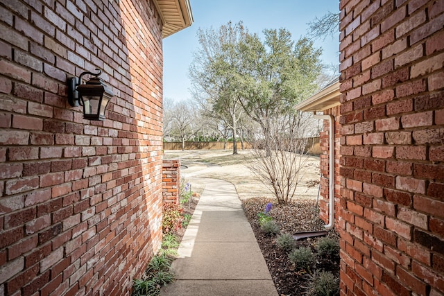 view of side of property featuring fence and brick siding