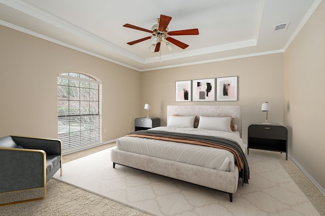 carpeted bedroom featuring ceiling fan, visible vents, baseboards, ornamental molding, and a tray ceiling