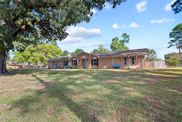 back of house with a yard, brick siding, a chimney, and fence