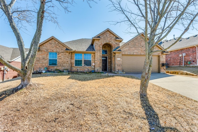 view of front of property featuring an attached garage, brick siding, driveway, and a shingled roof