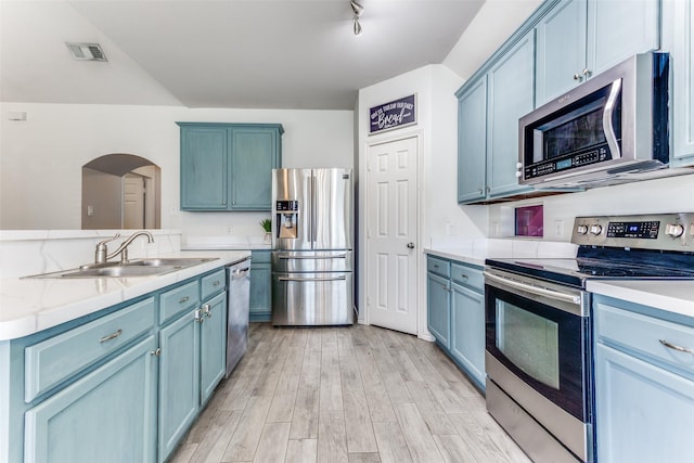 kitchen featuring visible vents, light wood-style flooring, a sink, appliances with stainless steel finishes, and blue cabinets