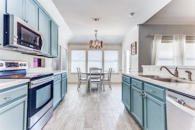 kitchen featuring visible vents, light wood finished floors, a sink, stainless steel appliances, and blue cabinets