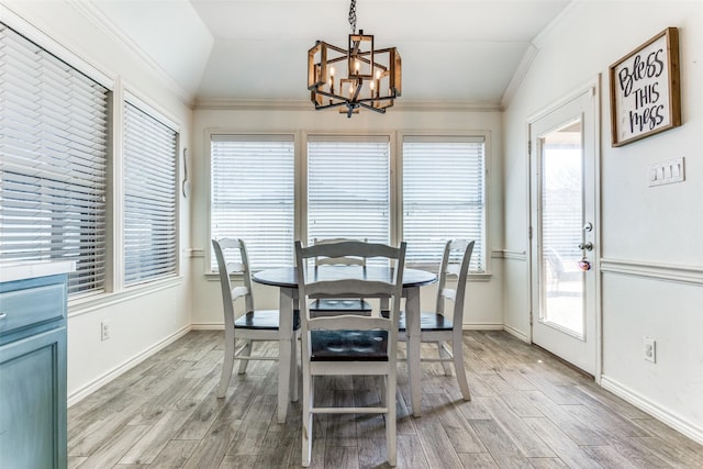 dining space featuring wood finish floors, lofted ceiling, a chandelier, and ornamental molding