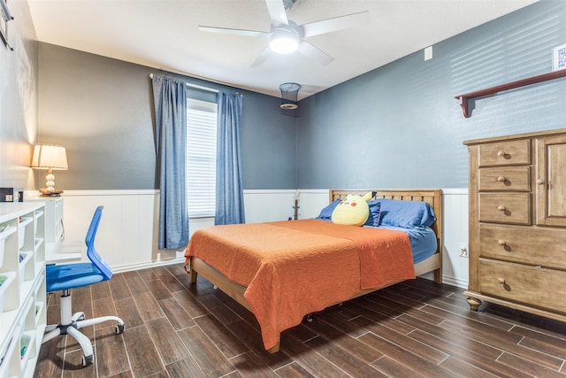 bedroom featuring wood finish floors, a ceiling fan, and wainscoting