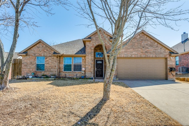 view of front of house with brick siding, a shingled roof, cooling unit, a garage, and driveway