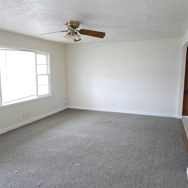 unfurnished room featuring a textured ceiling, ceiling fan, and baseboards