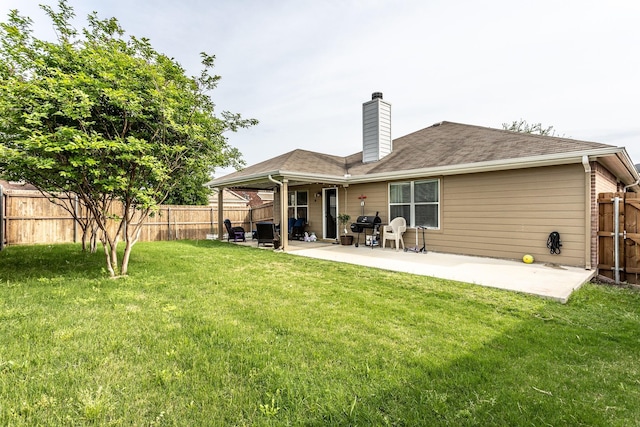 back of house featuring a fenced backyard, a chimney, a lawn, and a patio