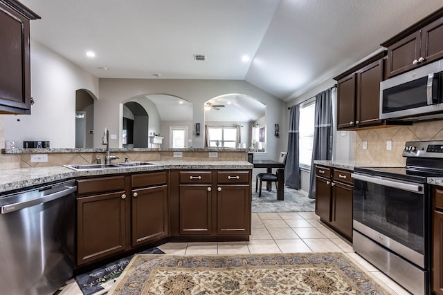 kitchen featuring dark brown cabinetry, a sink, visible vents, vaulted ceiling, and appliances with stainless steel finishes