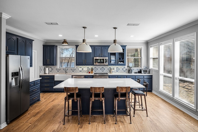 7811 Double Oaks Rd, Athens, TX 75752 - kitchen featuring stainless steel appliances, blue cabinets, ornamental molding, light countertops, and a breakfast bar area