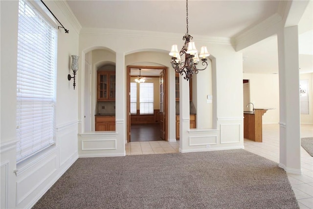 unfurnished dining area featuring a chandelier, arched walkways, light colored carpet, and crown molding