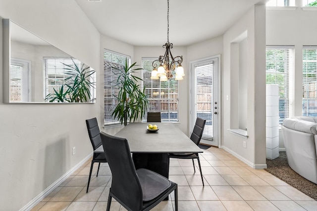 tiled dining area with a chandelier and baseboards