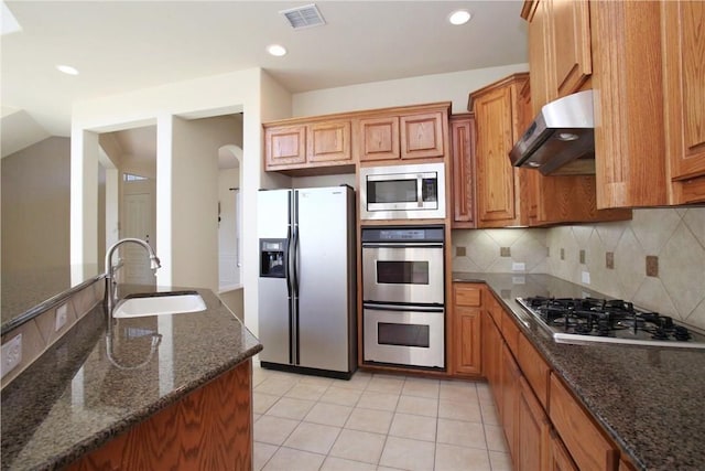 kitchen featuring visible vents, a sink, stainless steel appliances, under cabinet range hood, and backsplash