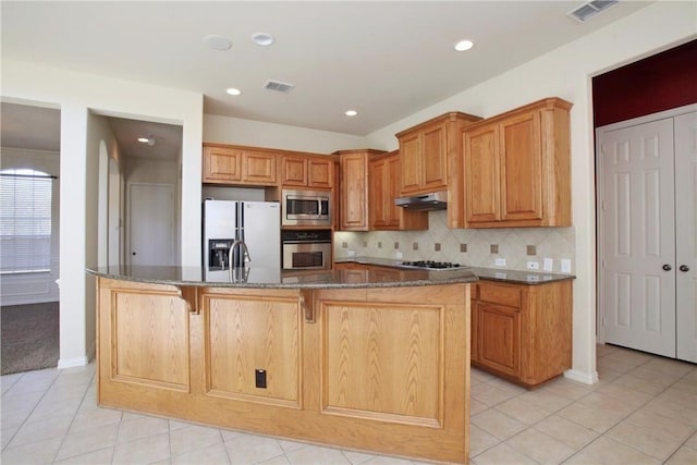 kitchen with stainless steel appliances, visible vents, under cabinet range hood, and decorative backsplash