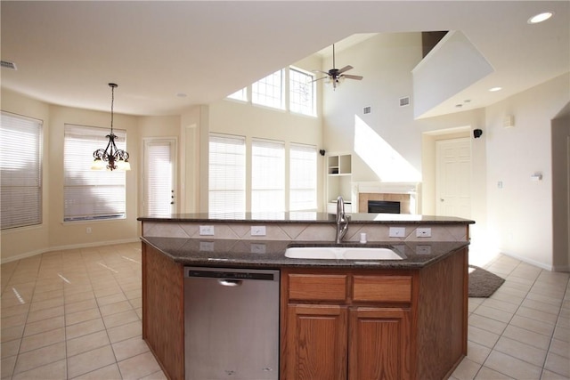 kitchen featuring a sink, light tile patterned floors, stainless steel dishwasher, and ceiling fan with notable chandelier