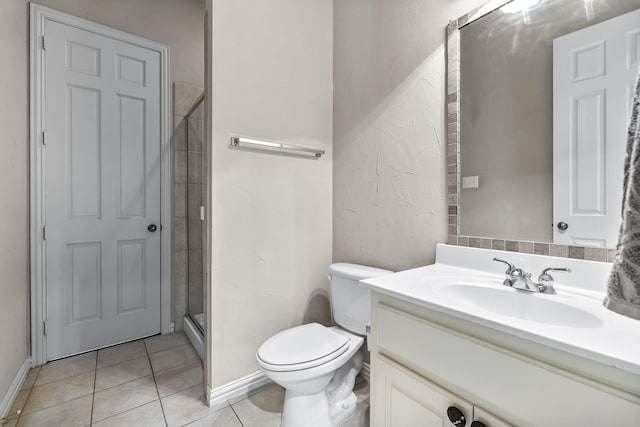 bathroom with toilet, vanity, baseboards, a shower stall, and tile patterned floors