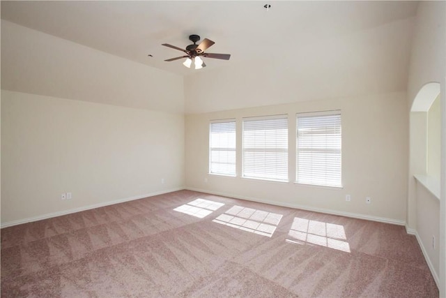 spare room featuring carpet floors, ceiling fan, baseboards, and vaulted ceiling