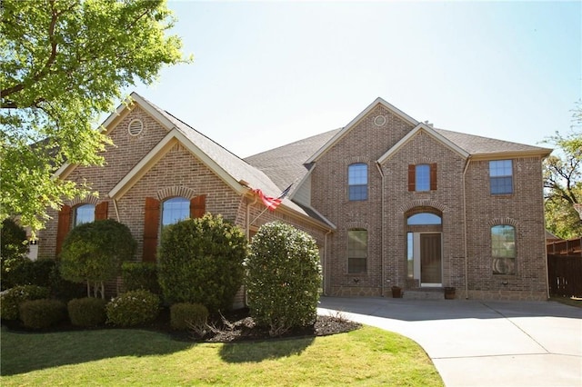 traditional-style house with concrete driveway, brick siding, and a front yard