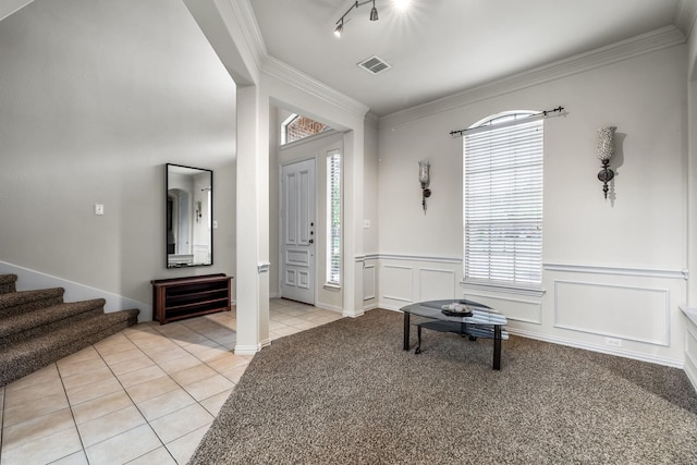 entrance foyer featuring light tile patterned flooring, a decorative wall, visible vents, ornamental molding, and stairway