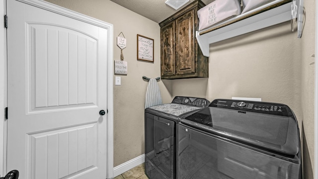 laundry room with cabinet space, baseboards, a textured ceiling, separate washer and dryer, and light tile patterned flooring